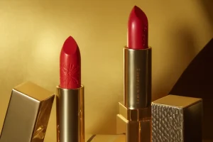 Engraved lipstick with gold cases on a golden background, styled for a luxury beauty product display.