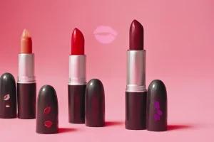ChatGPT said: Four engraved lipstick tubes in bold shades on a pink background, styled for a vibrant beauty showcase.